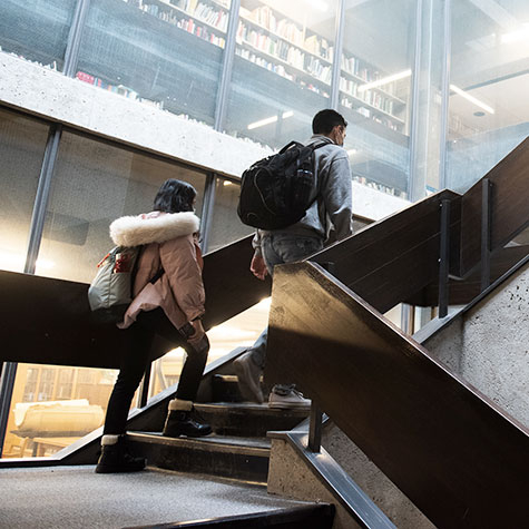 Two students walk up the stairs of the McLennan Library building