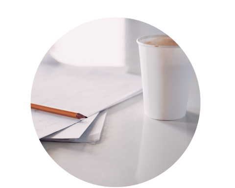 Cup of coffee next to paper and pencil